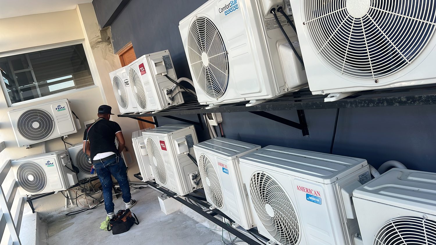 Banco de condensadores instalados en pared con técnico trabajando